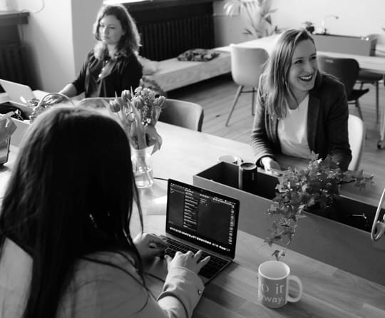 Three women with their laptops sitting on a table 