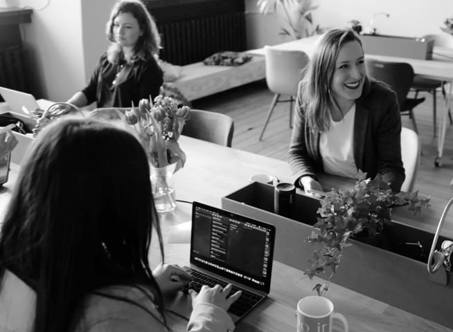 Three women with their laptops sitting on a table 